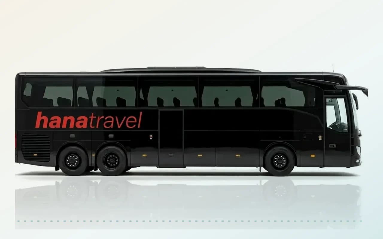 Een zwarte Mercedes-Benz Tourismo voor luchthaventransfers vanaf Antalya Airport op een witte achtergrond, zijaanzicht.